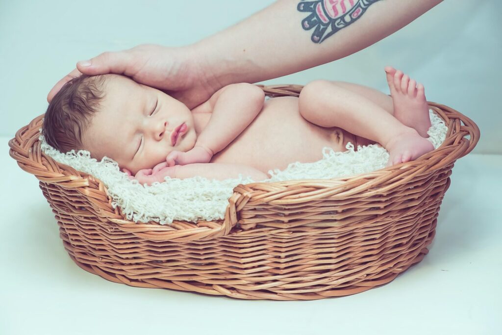 Bebé dormido en una canasta mientras su padre acaricia su cabeza con ternura.
